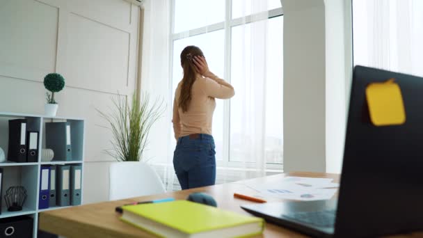 Молодая предпринимательница танцует у окна офиса во время рабочего перерыва — стоковое видео