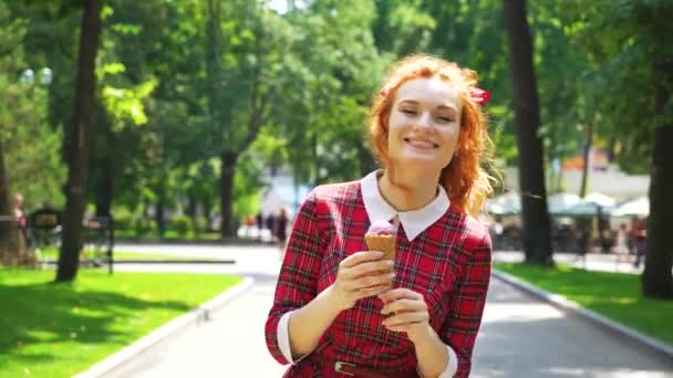 Positivo rossa ragazza a piedi nel parco e mangiare gelato — Video Stock