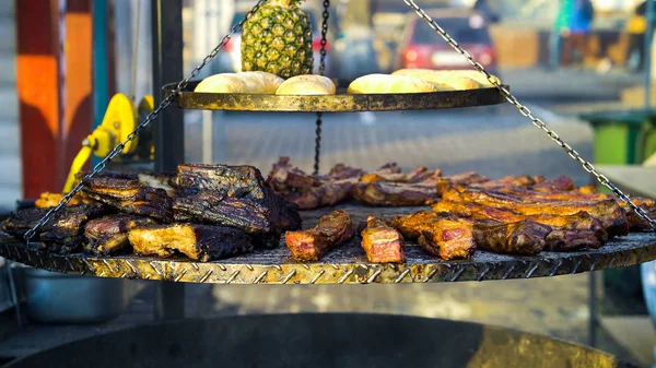 Big grill with pork ribs, bread and pineapple at street food festival