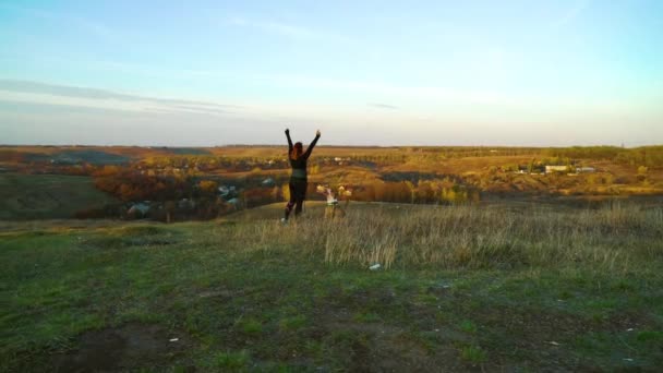 Young girl and American Staffordshire terrier together on hillside at sunset — Stock Video