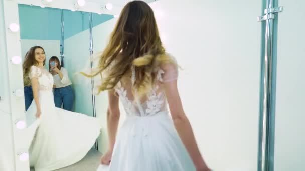 Ženské kamarádky fotit šťastnou nevěstu spinning před zrcadlem — Stock video