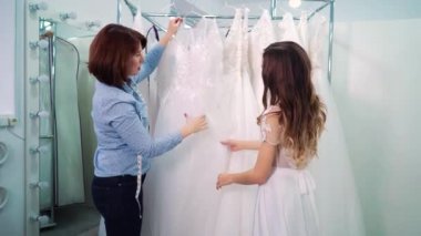 Bride and dressmaker choosing wedding gown in salon