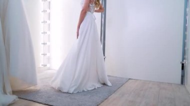 Beautiful girl trying on luxury dress in wedding salon