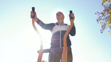 Pensive girl running on exercise bike outside