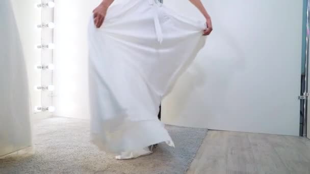 Smiling girl in wedding dress in front of big mirror with bulbs — Stock Video