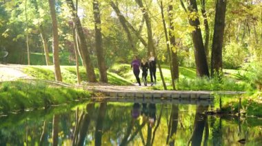 Athletic girls jogging across bridge over river in city park