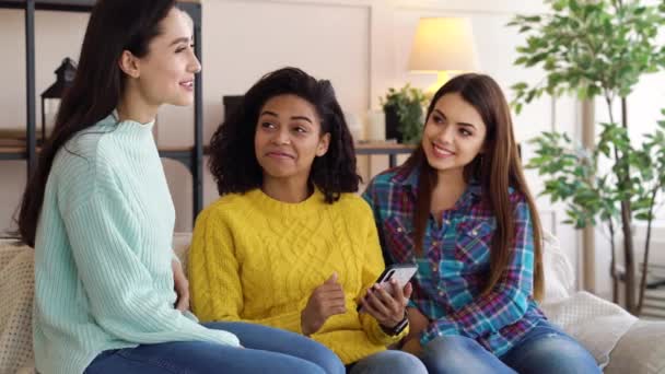 Colegas de quarto multirraciais alegres conversando e usando smartphone em casa — Vídeo de Stock