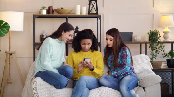 Group of multiracial girls sitting at home and looking at smartphone screen — Wideo stockowe