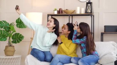 Happy multiracial girls taking selfie photo at home