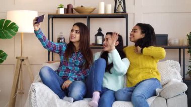 Cheerful girls sitting at home and live streaming using smartphone
