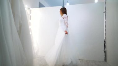 Young girl in wedding dress looking at mirror in salon