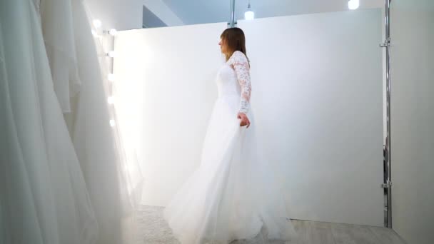 Young girl in wedding dress looking at mirror in salon — Stockvideo