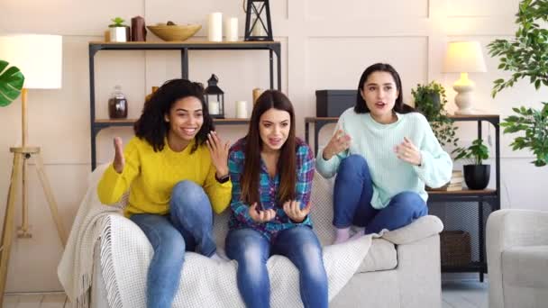 Багаторасові дівчата дивиться спортивний матч по телевізору вдома — стокове відео