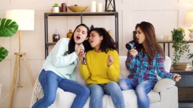 Happy girls enjoying karaoke party at home