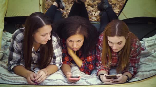 Multiracial girls using smartphones in tourist tent in autumn forest — Stock Video