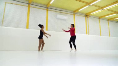 Spor giyim kuşağında formda kızlar spor salonunda paspasların üzerinde zıplıyorlar.