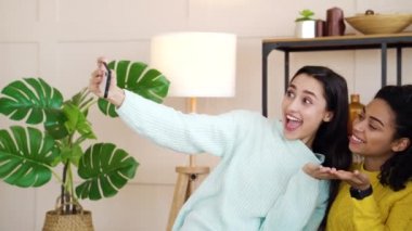 Gülümseyen çok ırklı bayan arkadaşlar evde selfie çekiyorlar.