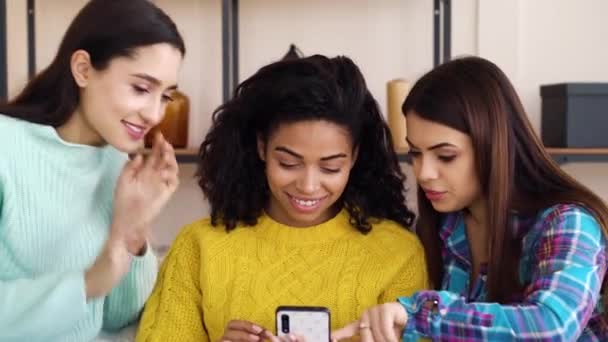 Chicas multirraciales felices viendo fotos en el teléfono inteligente en casa — Vídeo de stock