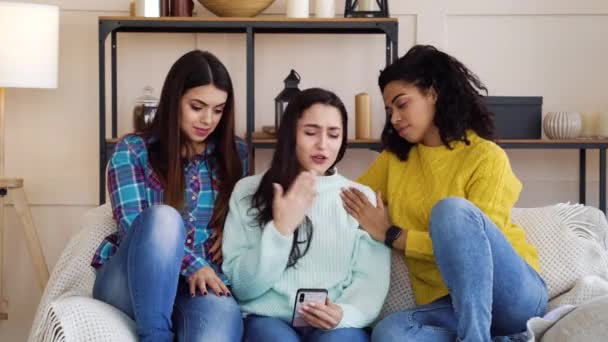 Заботливые девушки утешают своих злых друзей, используя смартфон дома — стоковое видео