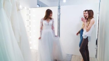 Genç gelin kuaförde gelinlik deniyor ve bayan arkadaşlar hayran.