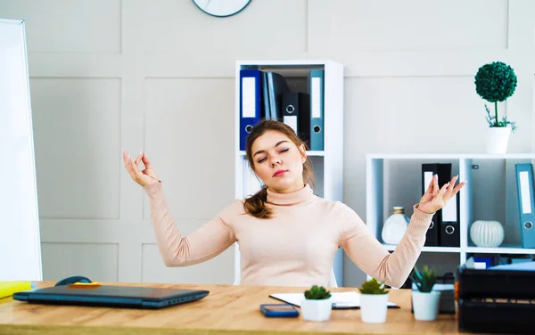 Young girl meditating in zen pose at workplace