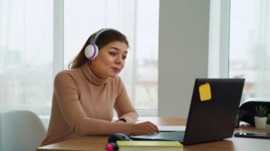 Young business woman in headphones having online meeting on laptop