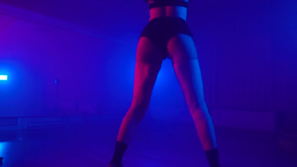 Sexy girl in shorts twerking in dark studio with fog and neon lights — Stockvideo