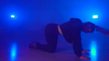 Young female performing seductive dance in dark studio with artificial fog