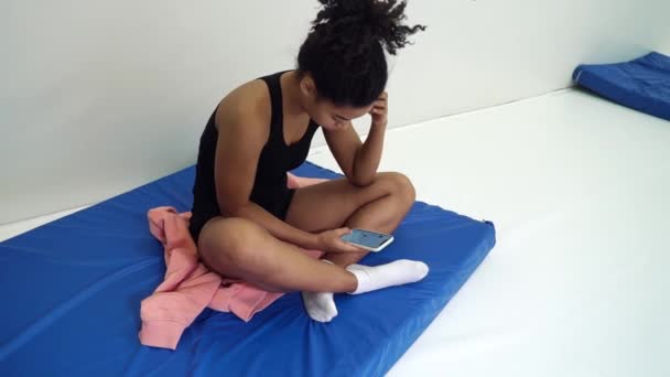 Sporty girl having break in training and using smartphone in gym — Stockvideo