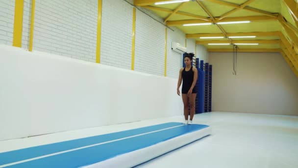 Flexible chica haciendo acrobacias voltea en la estera en el gimnasio — Vídeos de Stock