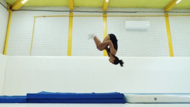 Black girl practicing back flips on mats in gym — Αρχείο Βίντεο