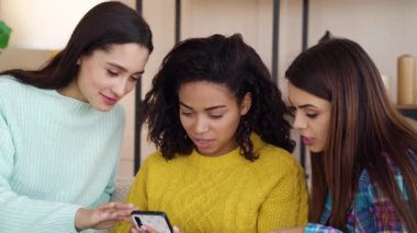 Pretty multiracial girls sitting at home and browsing internet on smartphone
