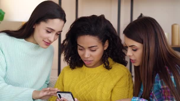Chicas bastante multirraciales sentadas en casa y navegando por Internet en el teléfono inteligente — Vídeo de stock