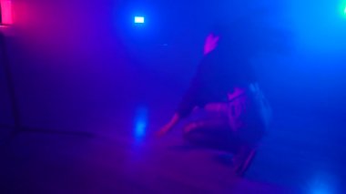 Sisli stüdyoda neon ışığıyla karanlıkta dans eden seksi kız.