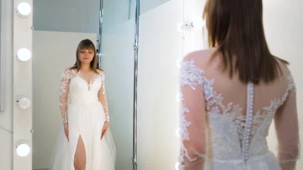 Specchio riflesso della bella sposa che prova l'abito da sposa nel salone — Video Stock