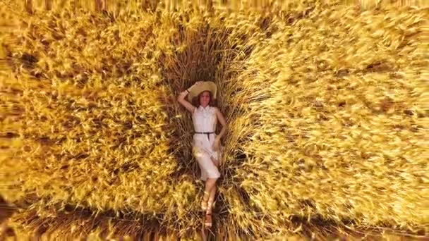 Fille romantique en robe blanche et chapeau de paille relaxant dans le champ de blé doré — Video