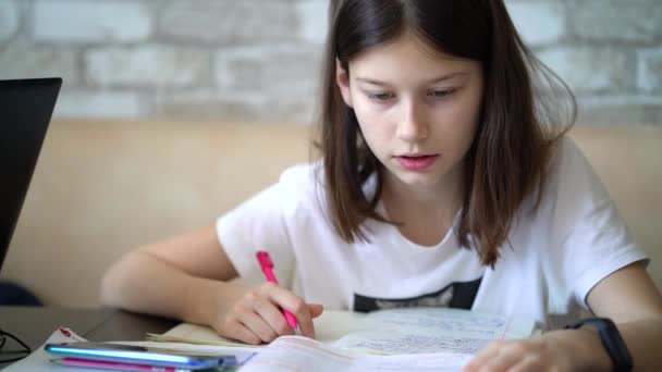 Schoolgirl doing written tasks of homework at home — Stock Video
