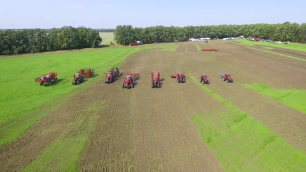 Фермерські машини їдуть в чергу на зеленому полі в сонячний день — стокове відео