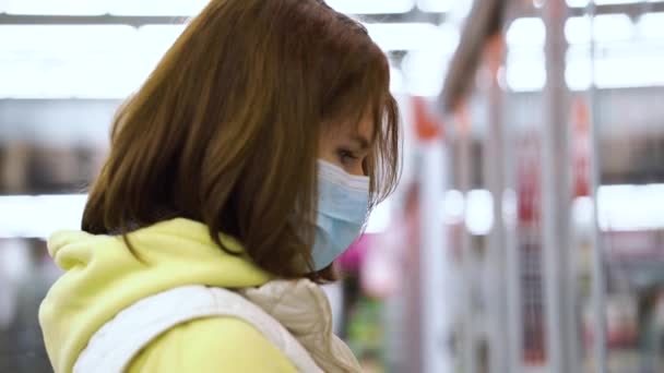 Jovem mulher na máscara escolhendo produtos no supermercado — Vídeo de Stock