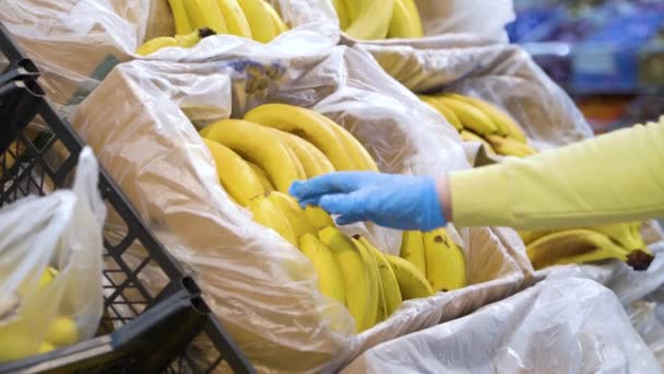 Mains féminines en gants médicaux prenant des bananes à l'épicerie — Video