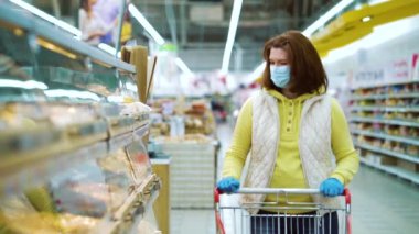 Tıbbi maskeli ev hanımı ve eldivenler süpermarketten taze hamur işi alıyor.