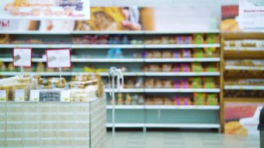 Tıbbi maskeli ve eldivenli bir kız süpermarketten alışveriş arabasıyla geçiyor.