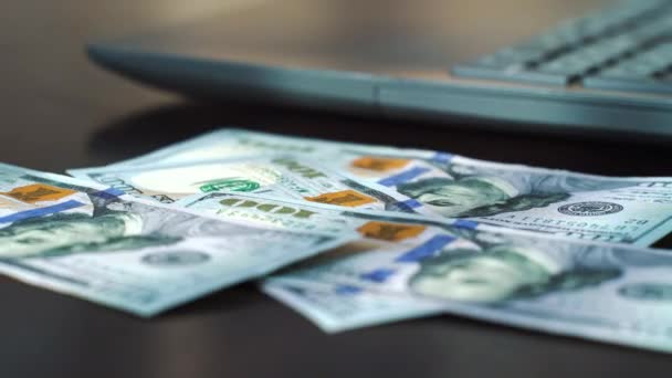 Billetes de dólar Timelapse cayendo en la mesa junto a la computadora portátil — Vídeos de Stock