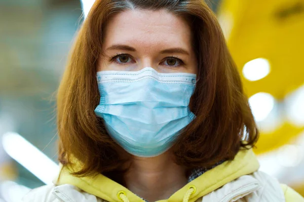 Tıbbi maskeli kadın, Covid19 salgını sırasında alışveriş merkezinde poz veriyor.