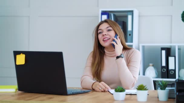 Довольно веселая девушка разговаривает по телефону в офисе — стоковое видео