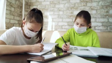 Coronavirus salgını sırasında evde çalışan maskeli kızlar.
