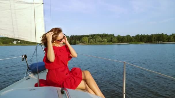 Kırmızı elbiseli güzel kadın yelkenli teknede tatilin tadını çıkarıyor. — Stok video