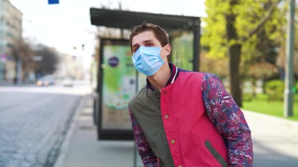 Jonge man met beschermend masker bij bushalte tijdens COVID pandemie — Stockvideo