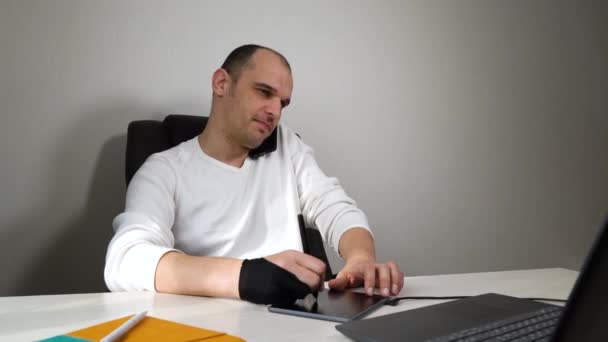Графічний дизайнер, який працює з дому під час карантину, використовуючи планшет і ноутбук — стокове відео