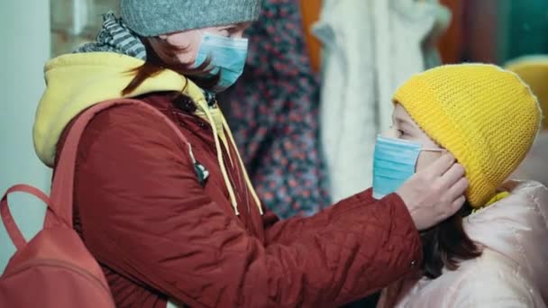 Мама надевает маску на маленькую дочь перед уходом из дома во время пандемии — стоковое видео
